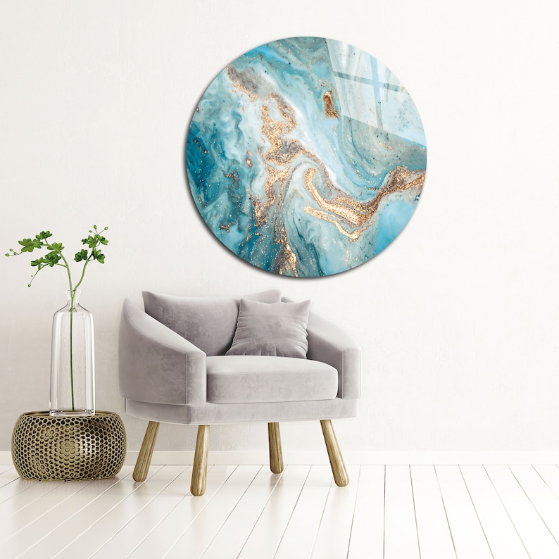 May include: A round wall art piece with a blue and gold abstract design. The design features swirling patterns and gold glitter accents.