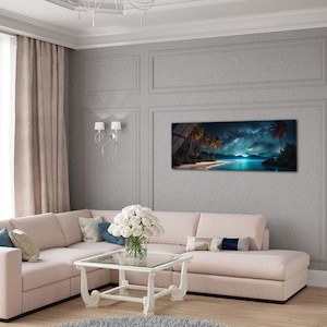 May include: A panoramic photograph of a tropical beach at night with palm trees, a starry sky, and a glowing moon reflecting on the water. The image is framed and hanging on a grey wall in a living room with a white sectional sofa and a white coffee table.