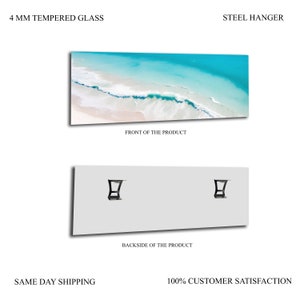 May include: A framed photograph of a beach scene with turquoise water and white sand. The frame is made of 4 mm tempered glass and has a steel hanger on the back.