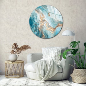 May include: A round wall art piece with a blue and gold abstract design. The design features swirling patterns and gold accents.