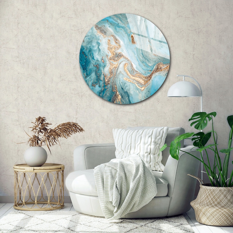 May include: A round wall art piece with a blue and gold abstract design. The design features swirling patterns and gold accents.