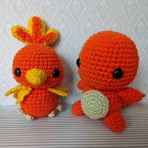 May include: Two crocheted stuffed toys, one orange with a yellow beak and a yellow and orange crest, the other a solid orange with black eyes.