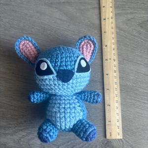 May include: Blue crocheted Stitch plush toy with pink ears and black eyes.