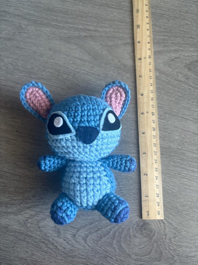 May include: Blue crocheted Stitch plush toy with pink ears and black eyes.