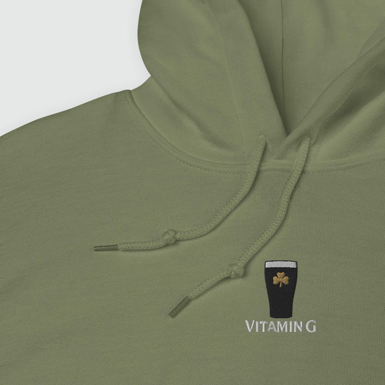 May include: Olive green hoodie with a drawstring. The hoodie features an embroidered design of a dark beer glass with a shamrock and the text "VITAMIN G" in white.