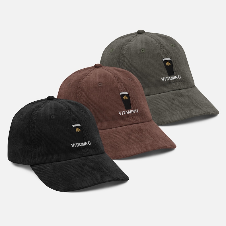 May include: Three corduroy baseball caps in black, brown, and olive green. Each cap features an embroidered design of a pint of stout with a shamrock and the text "Vitamin G". The caps have a curved brim and an adjustable strap.