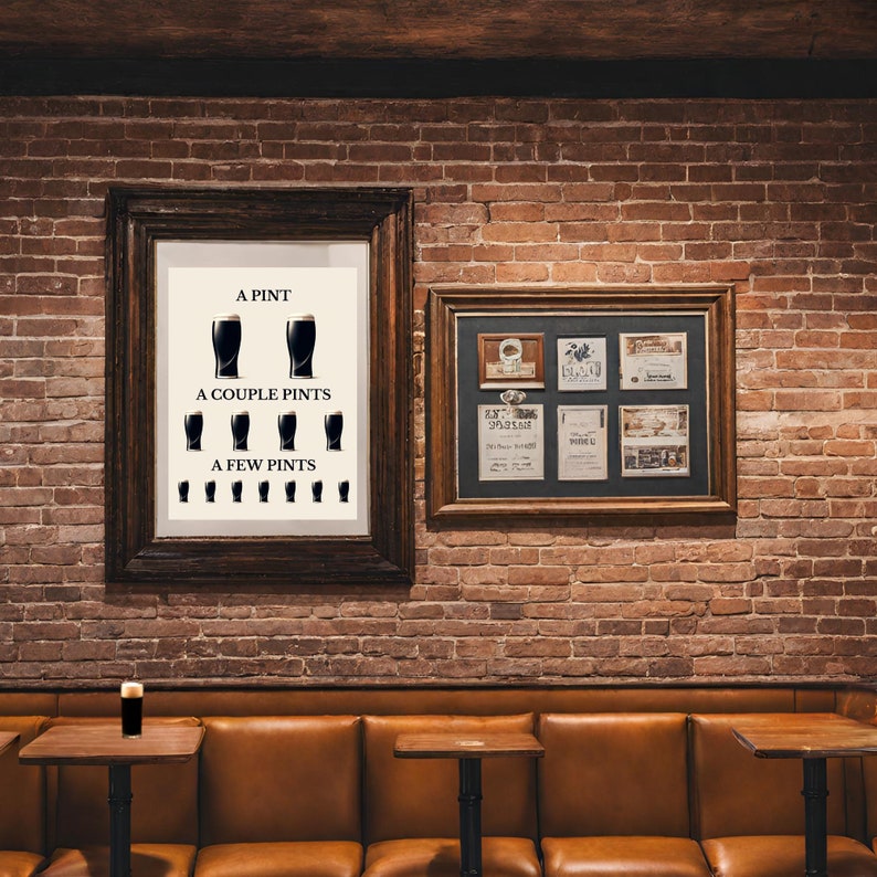 May include: Two framed artworks hang on a brick wall. One features a print with the text "A Pint, A Couple Pints, A Few Pints" and illustrations of beer glasses. The other frame contains several smaller framed items. A pint of beer sits on a small table.