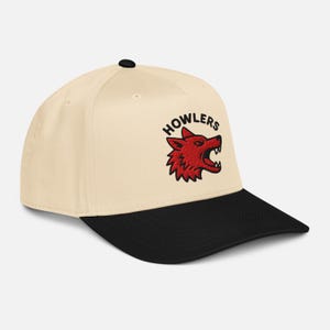 Op de afbeelding: Crèmekleurige baseballcap met een zwarte klep. De cap heeft het woord "HOWLERS" boven een rood wolfskoplogo met open kaken. Zwarte knop bovenop.