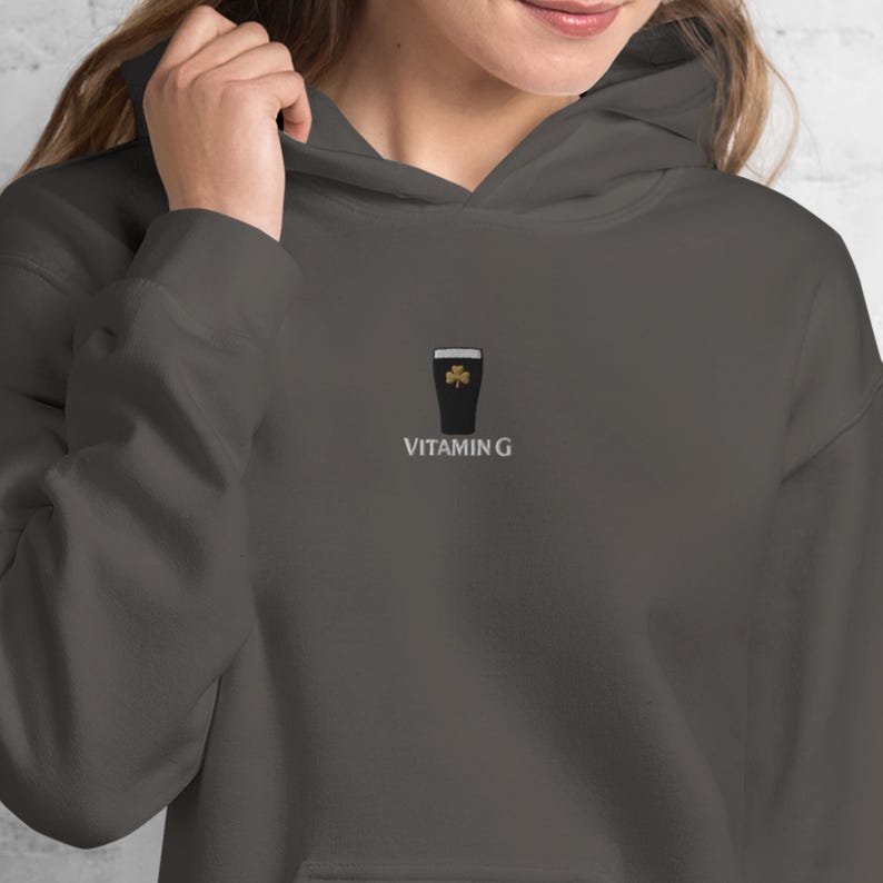 May include: Dark gray hoodie with a small embroidered design of a pint of stout with a shamrock and the text "VITAMIN G" below it. The hoodie has a drawstring hood and a front pocket.