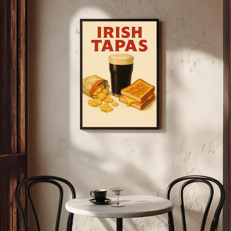 May include: A framed print featuring the words "IRISH TAPAS" in red. The image depicts a pint of dark beer, a bag of chips, and a grilled cheese sandwich. The print is displayed on a textured white wall.