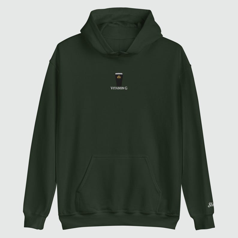 May include: Dark green hoodie with a front pocket and a hood. The hoodie features a small embroidered design of a coffee cup with a shamrock and the text "VITAMIN G". The sleeve has a small embroidered "St" logo.