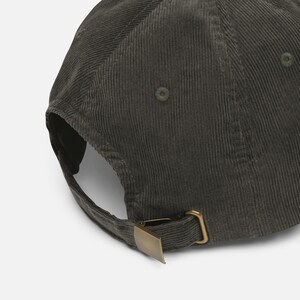 May include: A dark green corduroy baseball cap with a curved brim and adjustable metal clasp. The cap has a classic six-panel design and a tonal button on top. The fabric has a ribbed texture.