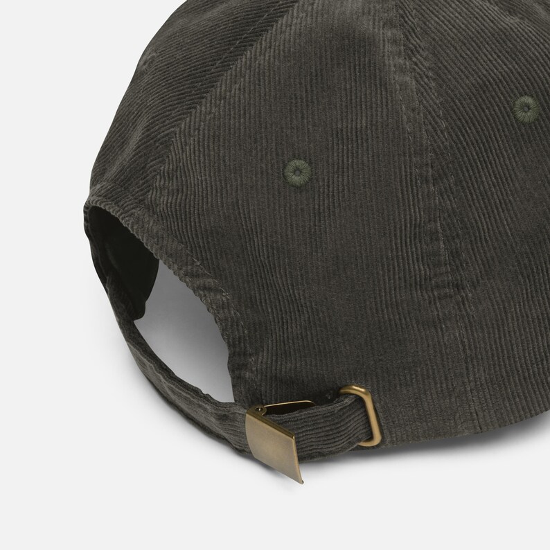 May include: A dark green corduroy baseball cap with a curved brim and adjustable metal clasp. The cap has a classic six-panel design and a tonal button on top. The fabric has a ribbed texture.