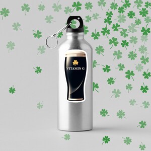 May include: A stainless steel water bottle with a sticker of a dark stout beer glass with the text "VITAMIN G" and a shamrock. The background features green shamrock patterns.