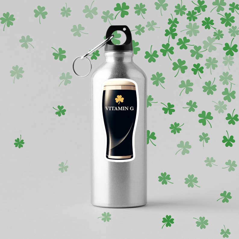 May include: A stainless steel water bottle with a sticker of a dark stout beer glass with the text "VITAMIN G" and a shamrock. The background features green shamrock patterns.