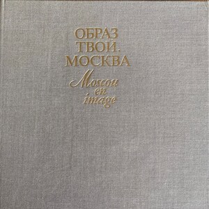 May include: A book cover with a textured, light gray surface. Gold lettering spells out "OBPA3 TBOИ. MOCKBA" and "Moscow en image". The cover has a simple, elegant design.