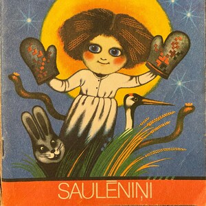 May include: A vintage children's book cover featuring a girl with blue eyes and red cheeks wearing mittens. The girl is standing in a field with a rabbit, a crane, and a snake. The book title is "SAULENINI" and the author is "VITAUTS LUDENS".
