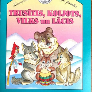 Könnte beinhalten: Kinderbuchcover mit einer Cartoon-Illustration eines Bären, zweier Wölfe, eines Hasen, der eine Trommel spielt, und eines roten Vogels. Der Titeltext lautet "TRUSĪTIS, KOLJOTS, VILKS un LĀCIS" in rosa Buchstaben. Der Hintergrund zeigt eine verschneite Landschaft.