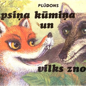 Könnte beinhalten: Ein Buchcover mit einem Fuchs und einem Wolf mit dem Titel "lapsina kumiņa un vilks znotinis" in schwarzem Text. Das Buchcover ist mit einem grünen Hintergrund und Blättern illustriert.