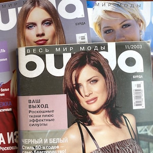 Può includere: Tre copie della rivista di moda russa "BuDa" con modelli di copertina e date di pubblicazione diverse. Le copertine della rivista presentano donne con diversi stili di capelli e abbigliamento. Il titolo della rivista è stampato in bianco e nero con una grande "a" rossa al centro.