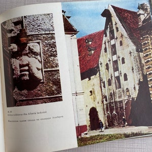 May include: A vintage photo of a building with a red roof and white walls. The building has many windows and a large arched doorway. The photo is from a book about the history of the building.
