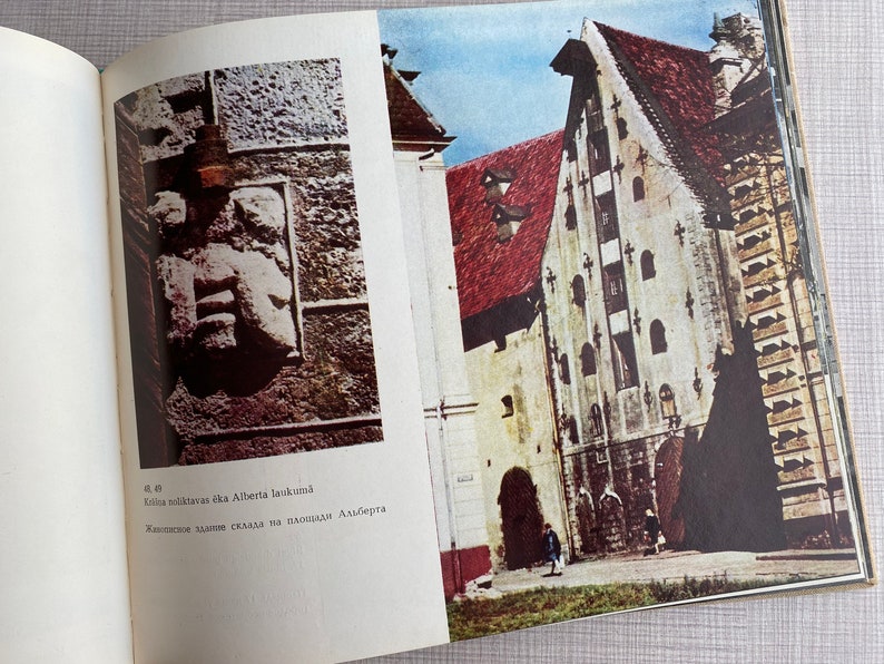 May include: A vintage photo of a building with a red roof and white walls. The building has many windows and a large arched doorway. The photo is from a book about the history of the building.
