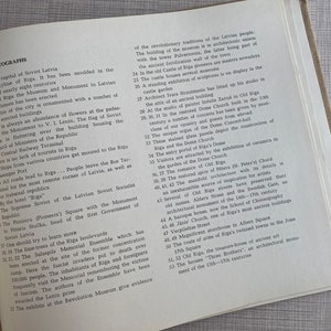 May include: A black and white photo of a book page with text about the city of Riga, Latvia. The text describes the city's history, architecture, and landmarks. The text includes the words "The skyline of Riga", "The Monument to V.I. Lenin", "The Dome Church", and "The Salaspils Memorial Ensemble".