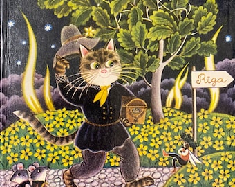 May include: A children's book cover with the title "Latviešu tautas-dziesmas". The illustration depicts a cat in a black outfit walking on a path towards a sign pointing to Riga. The scene includes mice, a bee, and yellow flowers.