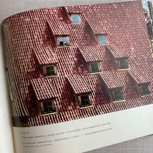 May include: A close-up of a red tiled roof with multiple dormer windows. The windows are all the same size and shape, and they are arranged in a symmetrical pattern. The roof is made of red tiles, and the windows are made of wood.