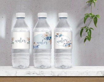 May include: Three clear plastic water bottles with labels featuring a watercolor design of fall leaves, pumpkins, and flowers. The labels say "water" in a handwritten font.
