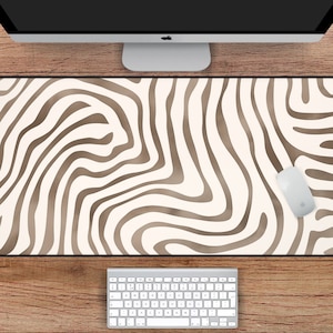 May include: A white desk mat with a brown abstract swirl pattern. The mat measures 31 inches by 15.5 inches.
