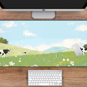 May include: A green and blue mousepad with a cartoon landscape featuring white clouds, green grass, and black and white cows. The mousepad is 31 inches by 15.5 inches.