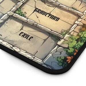 May include: A close-up of a stone-like game board with the words "Graveyard" and "Exile" printed on it. The board is surrounded by green foliage.