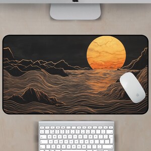 May include: A black and gold mouse pad with a stylized illustration of a sun setting over a wavy ocean. The sun is a bright orange and yellow color, and the waves are a light gold color.