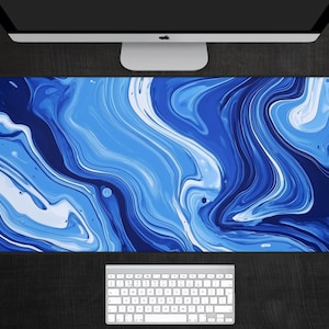May include: Abstract blue and white marble design desk mat. The design features swirling, flowing lines of blue and white paint.