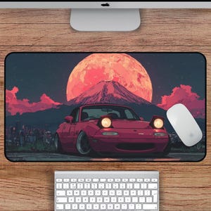 Puede incluir: Alfombrilla de rat&oacute;n rectangular con un coche deportivo rojo con faros emergentes sobre un fondo de monta&ntilde;a, un gran sol rojo y un paisaje urbano. La alfombrilla mide 56 cm por 30 cm.