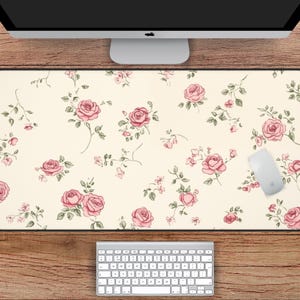 Puede incluir: Una alfombrilla de escritorio blanca con un patrón floral rosa. La alfombrilla mide 78,7 cm por 39,4 cm.