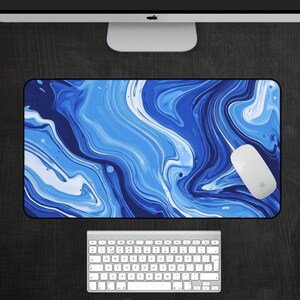 May include: Blue and white abstract marble design desk mat. The mat has a swirling pattern of blue and white paint.