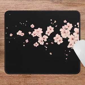 Puede incluir: Alfombrilla de rat&oacute;n negra con un dise&ntilde;o de flores de cerezo rosas sobre un fondo negro.