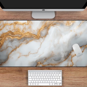 May include: A white and gold marble desk mat with a modern design. The mat measures 31 inches by 15.5 inches.