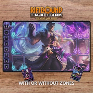 May include: A rectangular playmat for the "Riftbound League of Legends Trading Card Game" featuring a character illustration in shades of purple and blue. The mat has zones for card placement and the text "WITH OR WITHOUT ZONES". Two trading cards are visible.