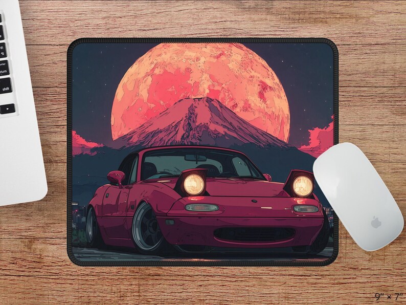 Puede incluir: Alfombrilla de rat&oacute;n con un coche deportivo granate con faros emergentes, sobre un fondo de un gran sol rojo y una monta&ntilde;a. La alfombrilla es rectangular, con dimensiones de 22,86 cm x 17,78 cm.