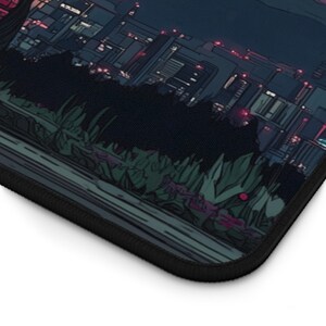Puede incluir: Una alfombrilla de rat&oacute;n negra con una ilustraci&oacute;n estilizada de un paisaje urbano nocturno. La obra de arte representa edificios con ventanas iluminadas y un primer plano oscuro con follaje. La alfombrilla tiene un borde negro.
