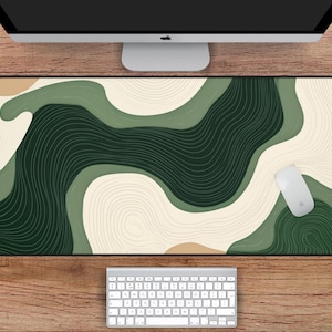 May include: A large rectangular desk mat with an abstract design in green, beige, and tan. The mat measures 78.7 cm by 39.4 cm. A white mouse and keyboard are visible.