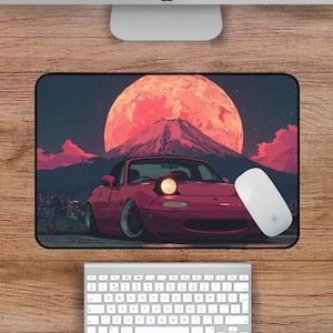 Puede incluir: Alfombrilla de rat&oacute;n rectangular con un coche deportivo rojo, una monta&ntilde;a y una gran luna naranja en el fondo. La alfombrilla mide 45,7 cm por 30,5 cm.