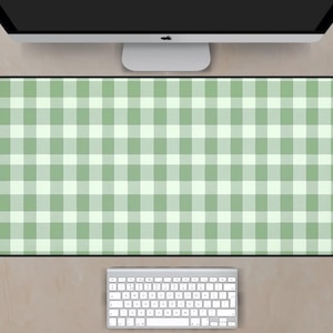 May include: A rectangular desk mat with a green and white gingham pattern. The mat is positioned beneath a computer monitor and above a silver keyboard. The color scheme is light and airy, suitable for a workspace.