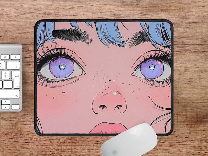Op de afbeelding: Een roze en blauwe muismat met een afbeelding van een vrouwen gezicht met paarse ogen. De vrouw heeft blauw haar en sproeten.