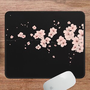 Puede incluir: Alfombrilla de rat&oacute;n negra con un dise&ntilde;o de flores de cerezo rosas. Las flores de cerezo est&aacute;n dispuestas en un patr&oacute;n fluido a trav&eacute;s de la alfombrilla de rat&oacute;n.
