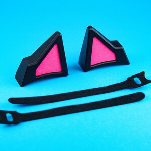 May include: Black cat ear headband accessories with pink inner ear detail. Includes two black cat ear pieces and two black straps for attachment. The ears are made of a hard plastic material.