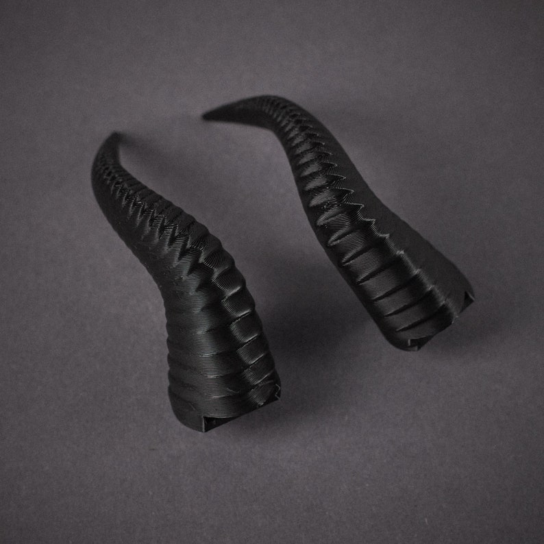 May include: Two black, 3D printed horns. The horns are curved and have a textured surface.